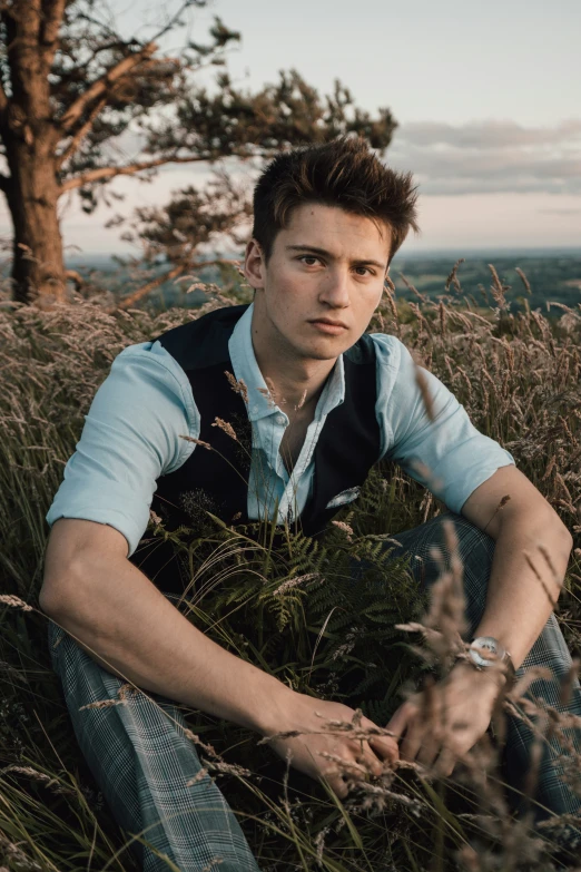a young man is sitting in the tall grass