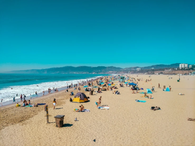 many people are at the beach near some water