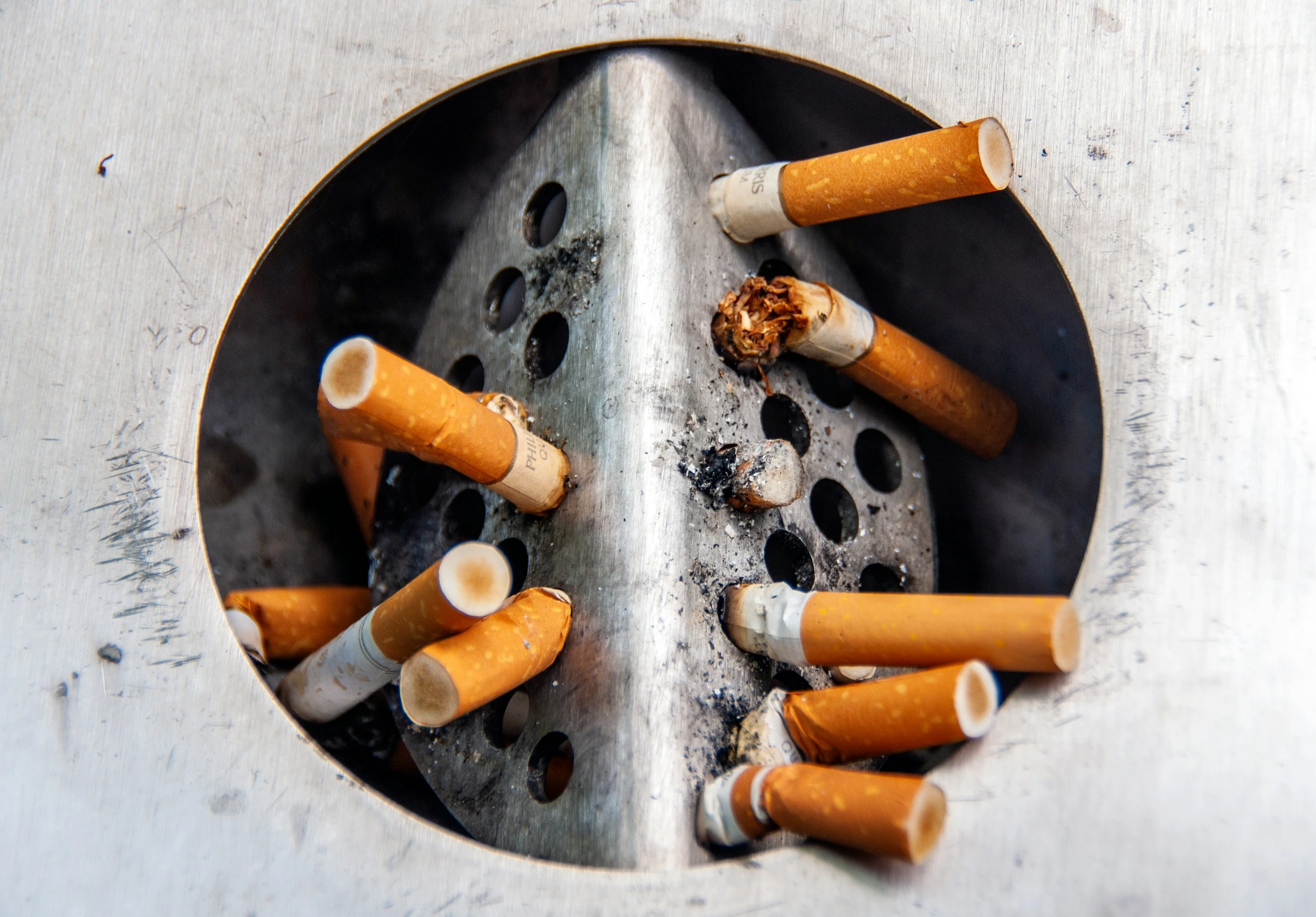 several cigarettes are in a silver ashtray