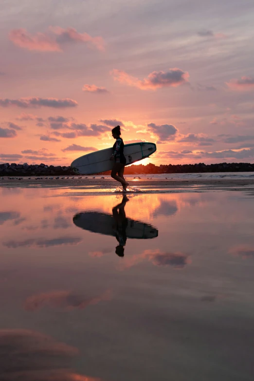 a man is walking on the beach holding a surfboard