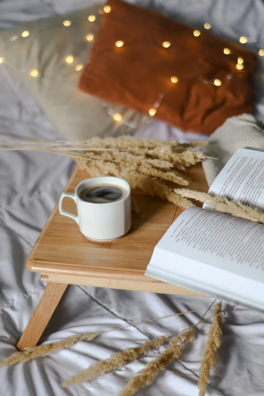 an open book, coffee cup and books on a wooden tray