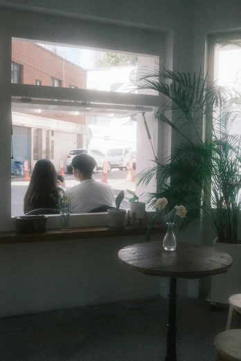 two people are sitting near the window at a coffee shop