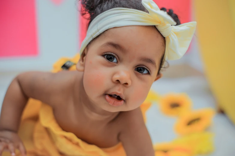 a young baby is wearing a yellow dress and bow