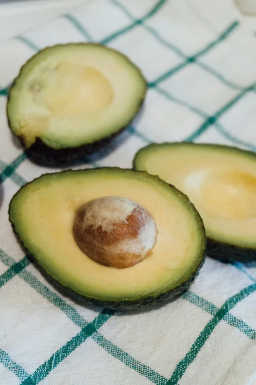 three pieces of avocado cut in half on a towel