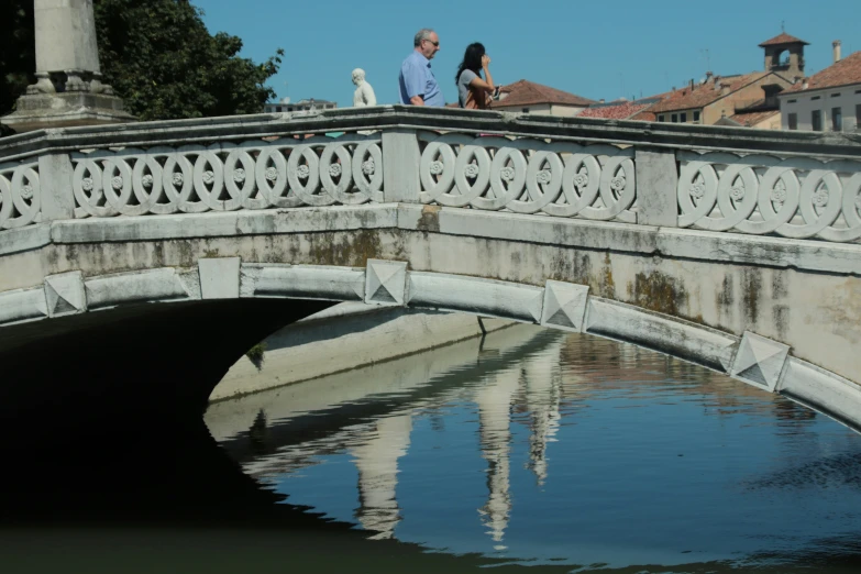 the bridge is reflecting the blue water in the pond