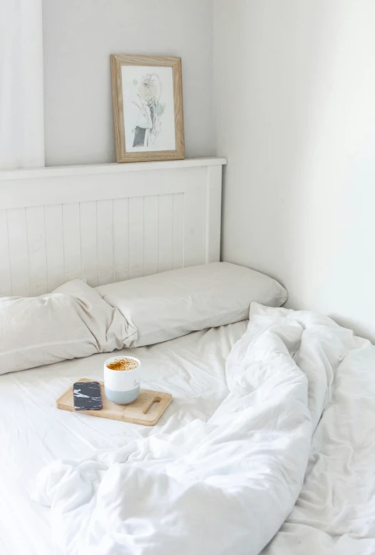 an unmade bed with a tray and coffee on it