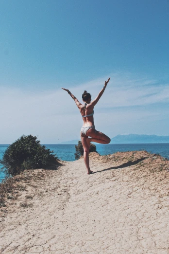 a girl is doing yoga on the beach