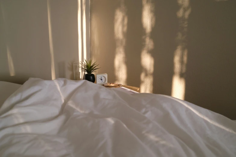 the shadow of a wall is seen behind the white sheets on the bed