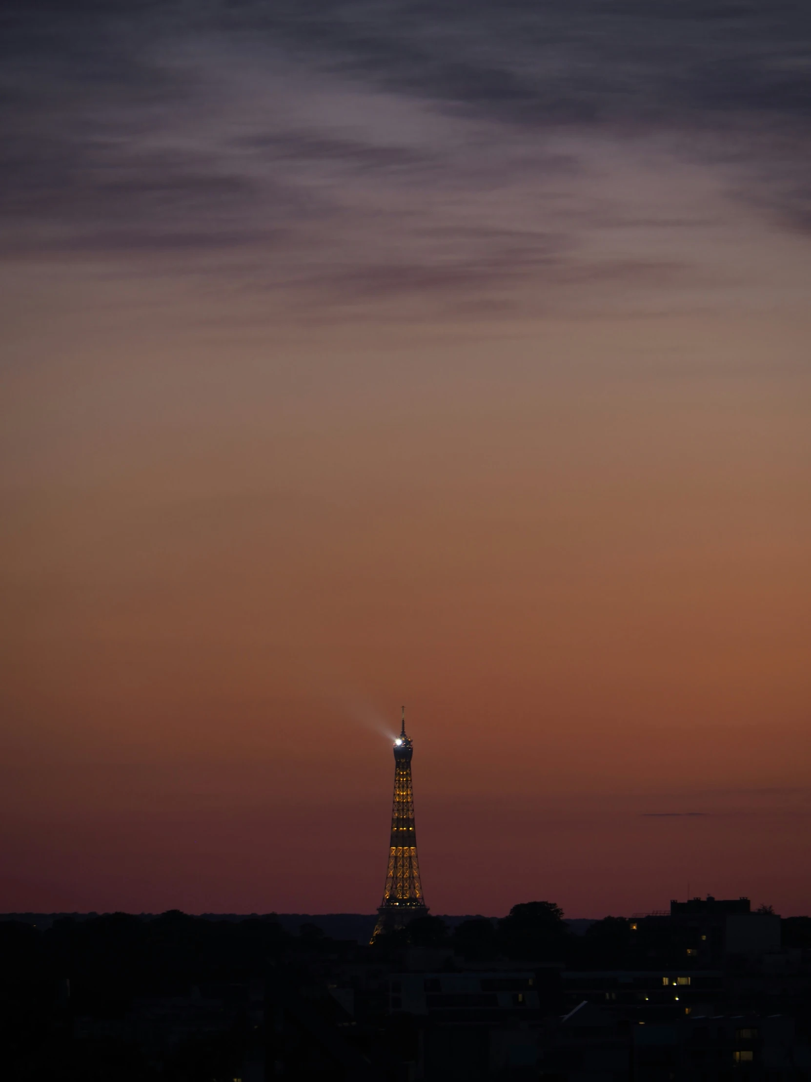 a large light tower stands in the distance