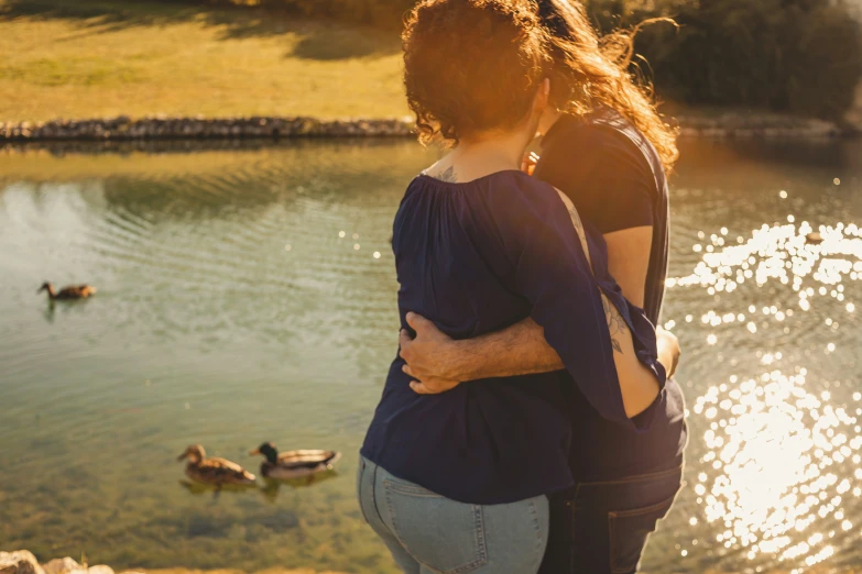 the two people are hugging near the lake