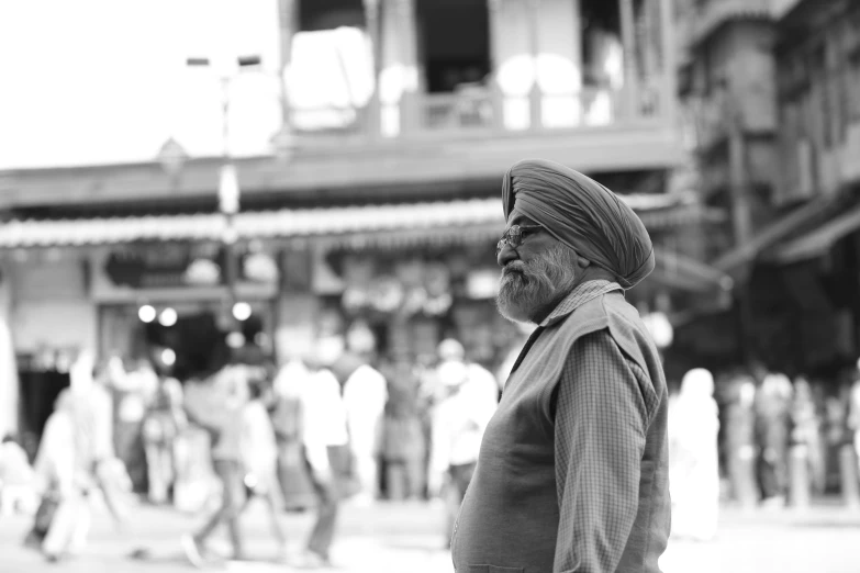 an old man in a turban walks through the street