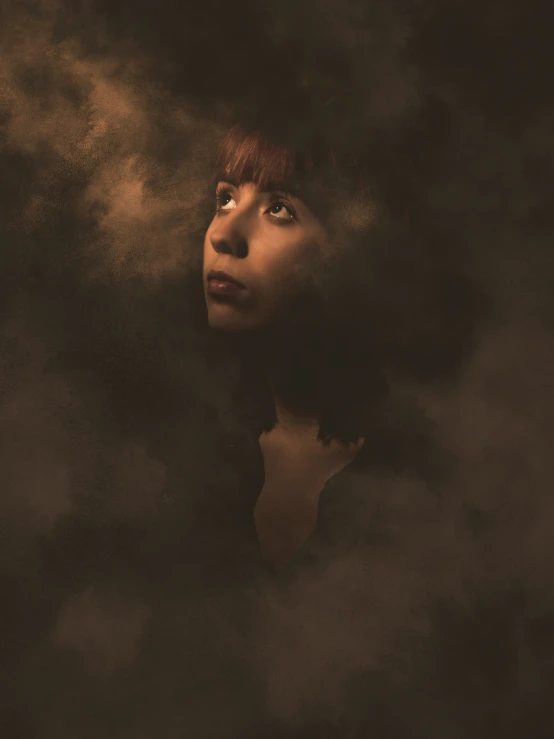 the young woman's face looks up through the dark smoke