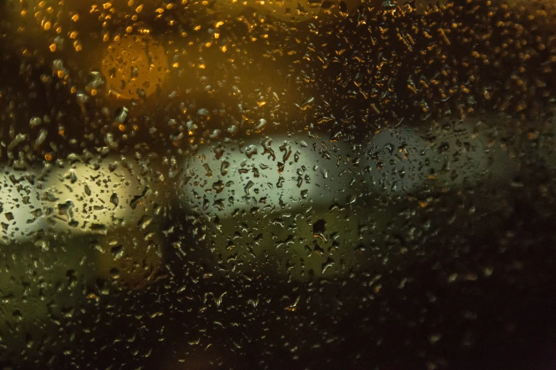 the view of two cars from inside a car through a rain covered window