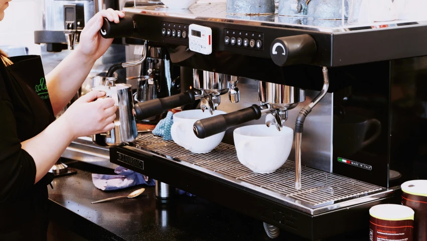 woman working in restaurant using espresso machine for coffee