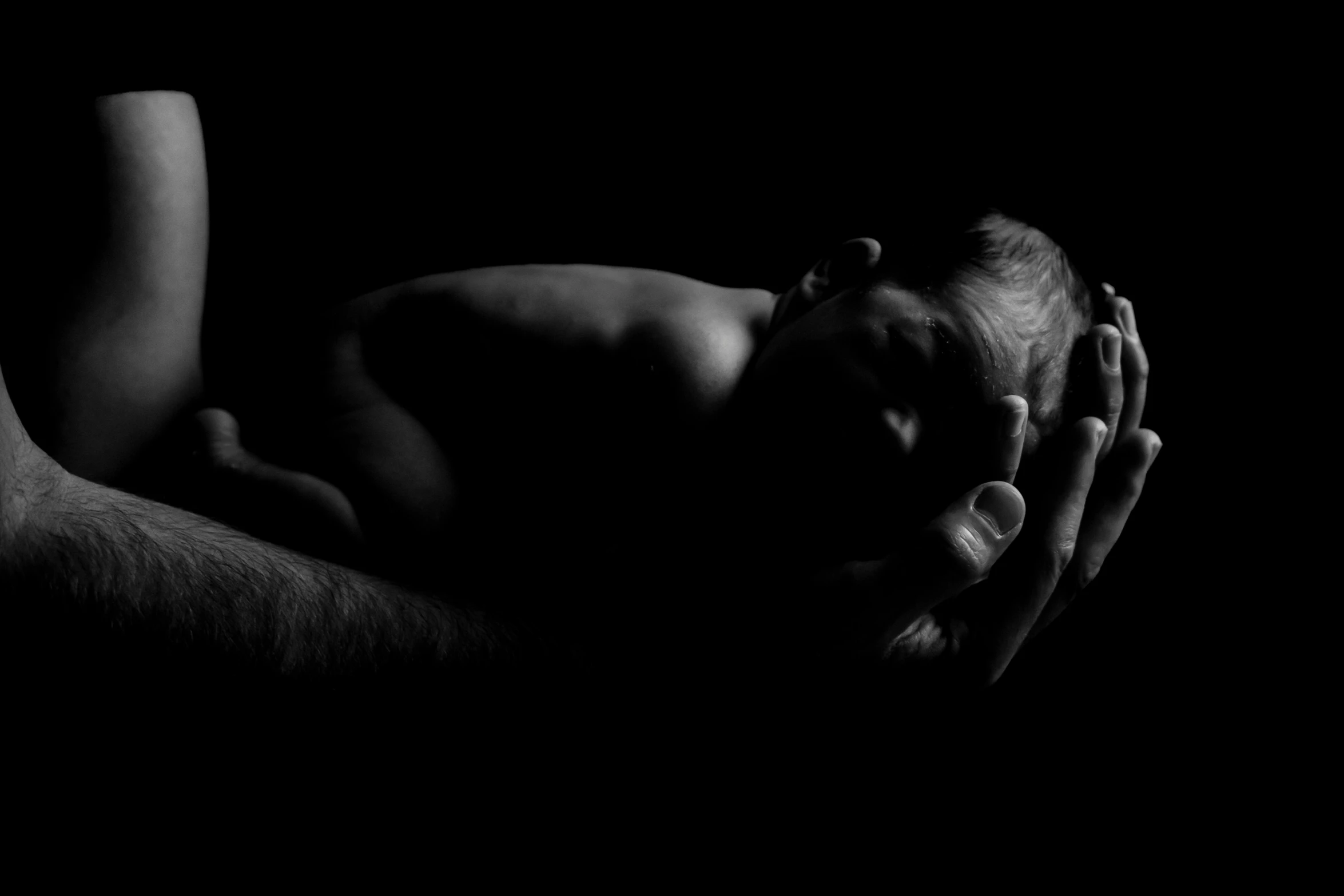 a man is laying in the dark holding his hands to his chest