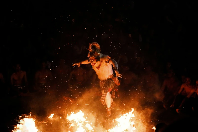 a man on a motorcycle doing tricks over a pile of fire