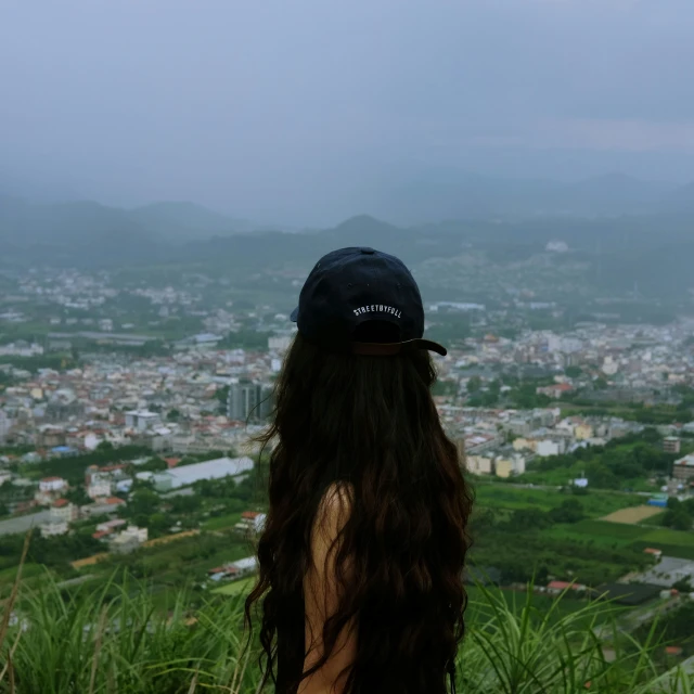 the back of a woman's head with long hair overlooking a city below