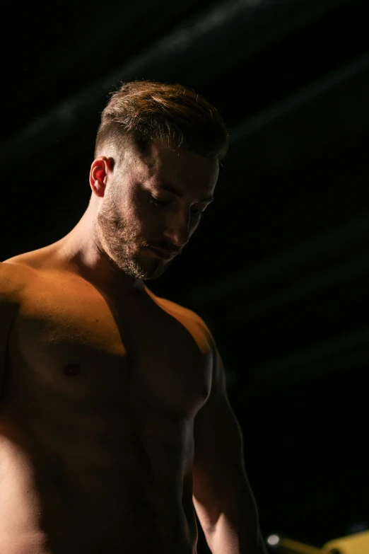 a man posing for the camera shirtless in a dark room