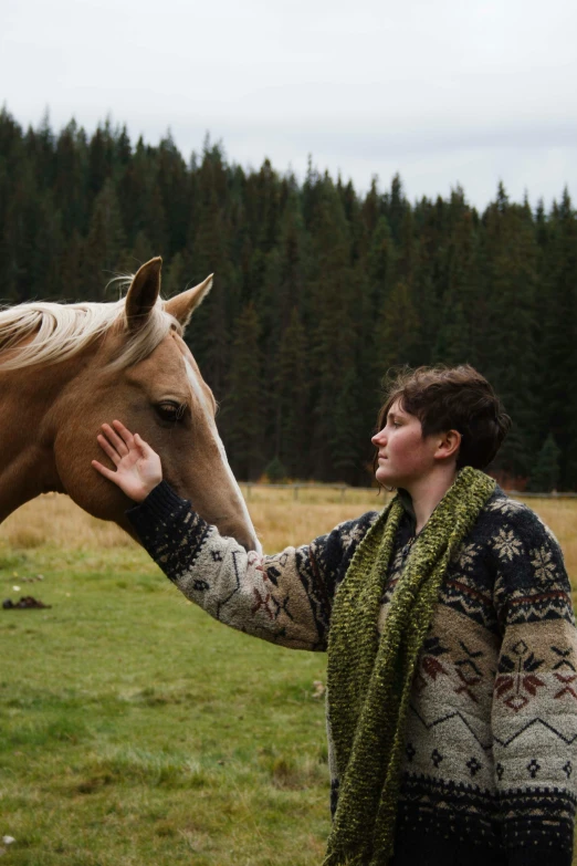 a woman feeding a horse by a string on the field