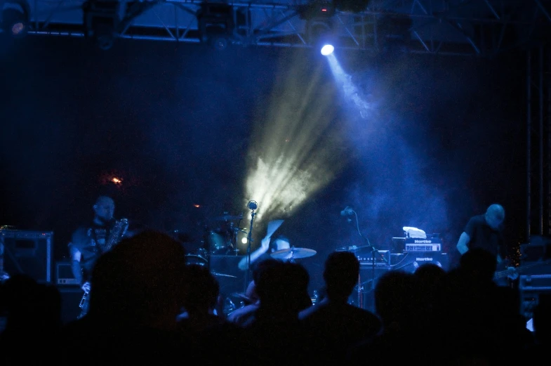 a concert with the lighting turned on is being viewed from behind an audience
