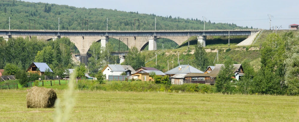 some hay and houses in front of a bridge