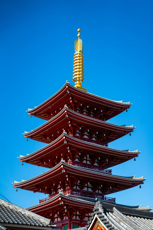 the pagoda is tall and orange against the blue sky