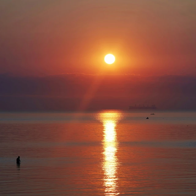 a very bright sun on the horizon over a large body of water