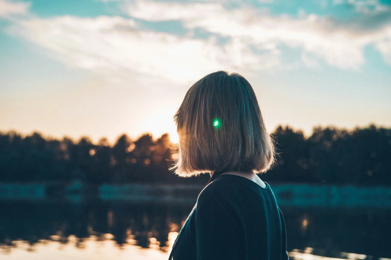 a young woman standing on a pier watching the sun set