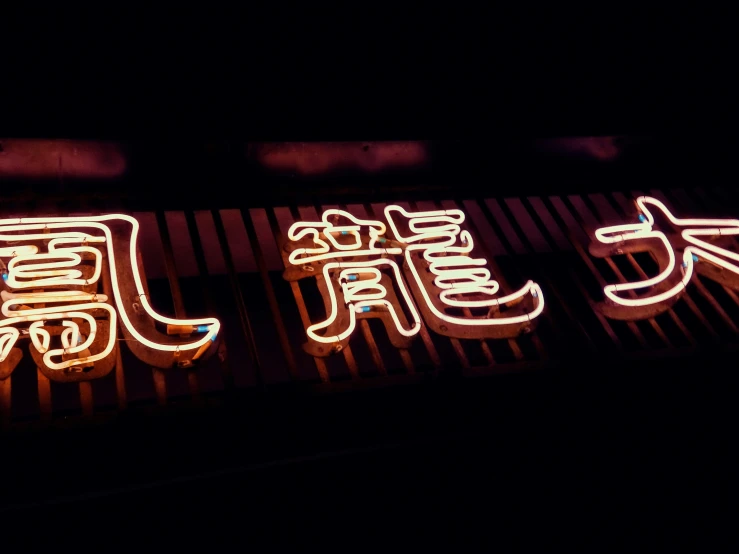 a lit up restaurant sign displaying chinese characters