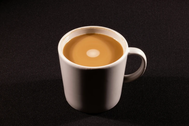 a white cup is sitting on a black surface