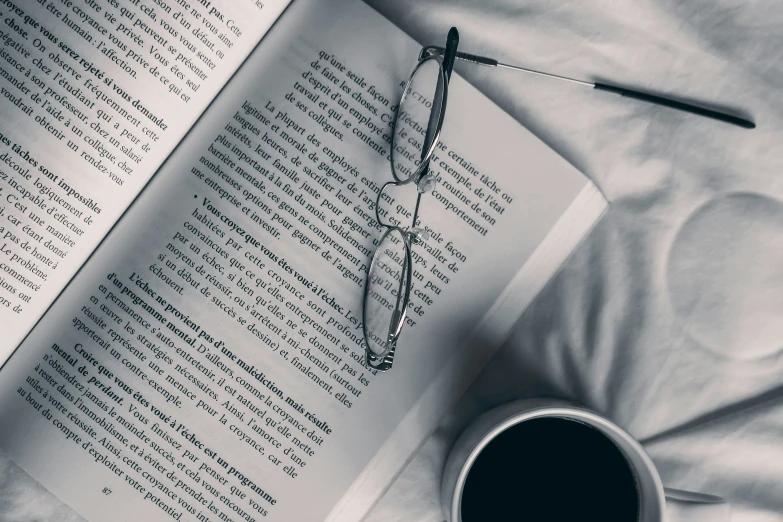 a cup of coffee and an open book on top of a bed