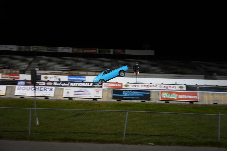 a blue race car in mid air on a track