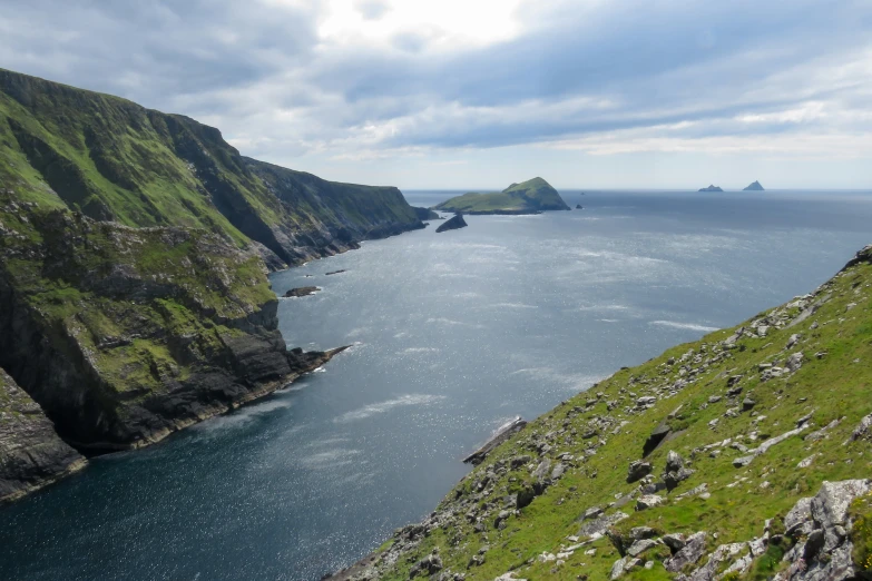 an island off the side of a mountain with green grass and rocks