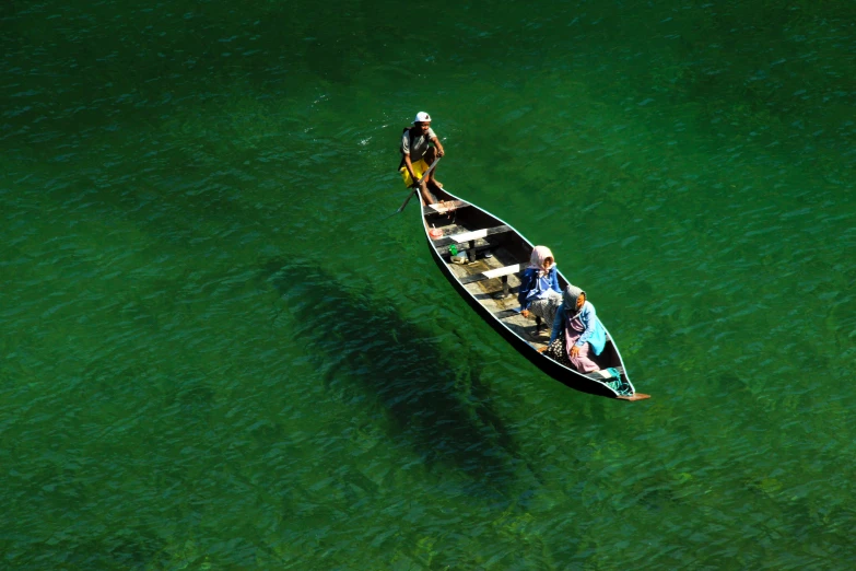 two men paddling their canoe down a shallow river
