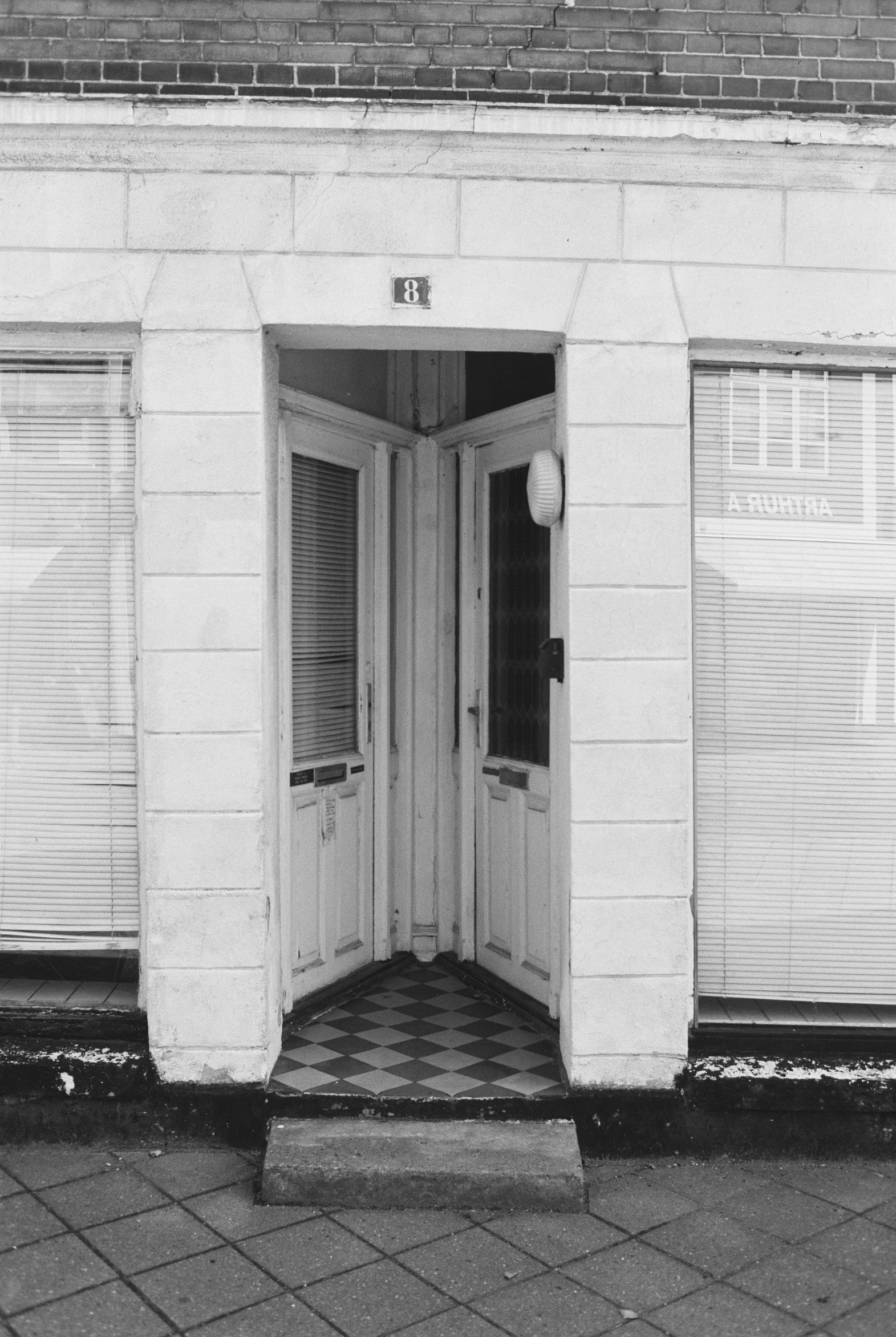 an entrance to a white building with glass doors and shutters