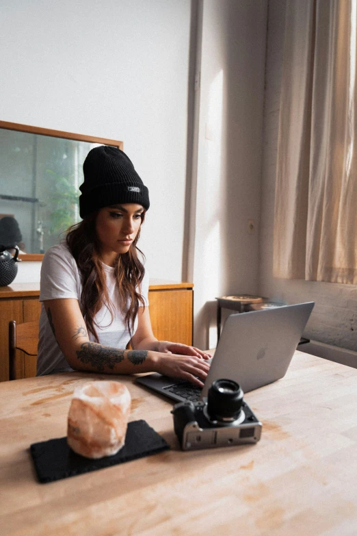 a young woman typing on her laptop at the kitchen table