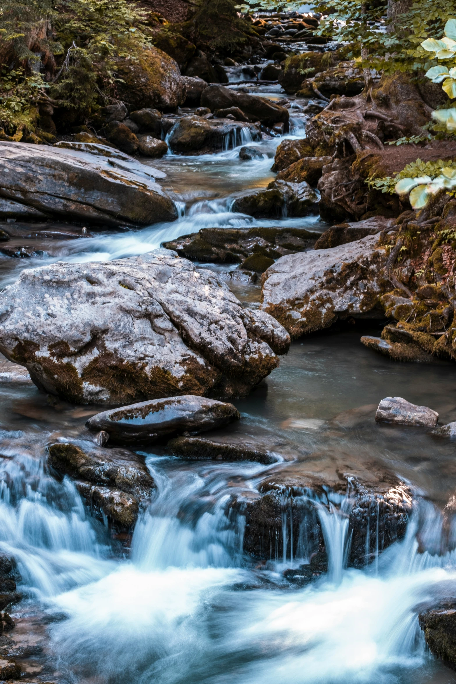 a waterfall surrounded by large boulders and greenery