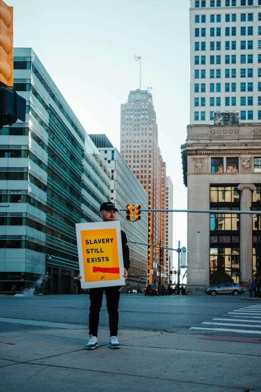 a man holding up a sign on the sidewalk