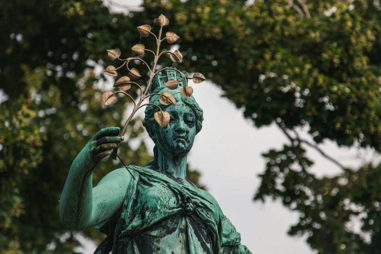 a statue in a park is holding a flower