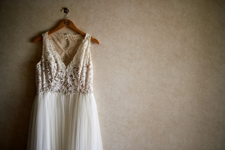 a white dress hangs on a wall with a clothes rail