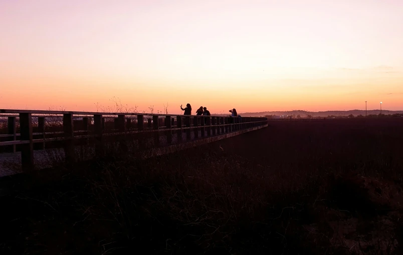 a group of people walking on top of a wooden bridge