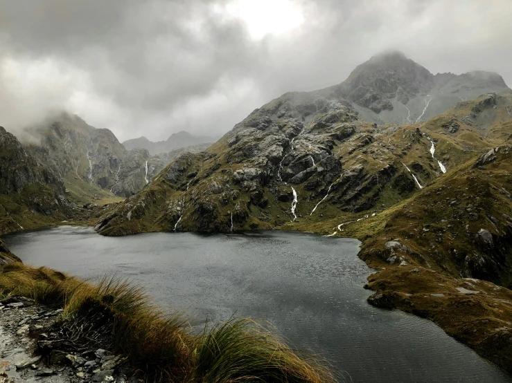 a mountain lake with snow and greenery around it