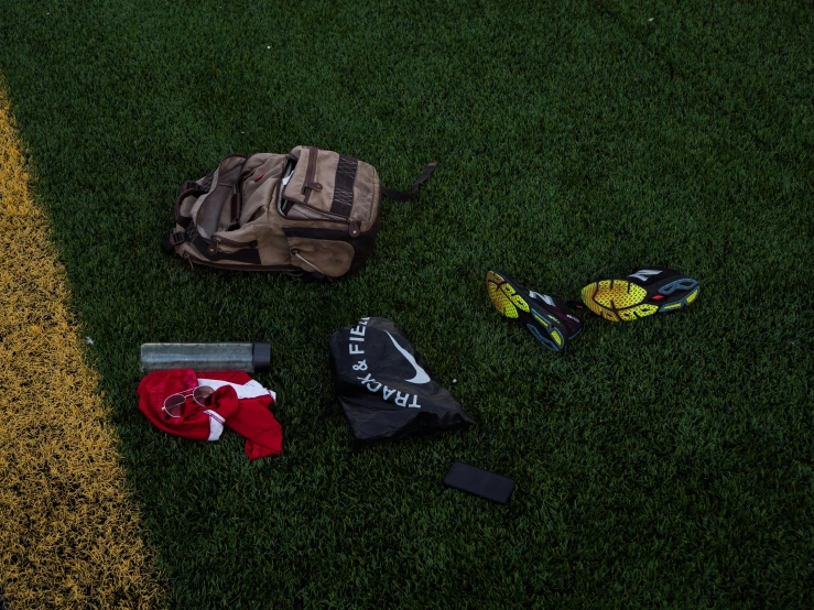 a group of backpacks and mitts sit on the side walk