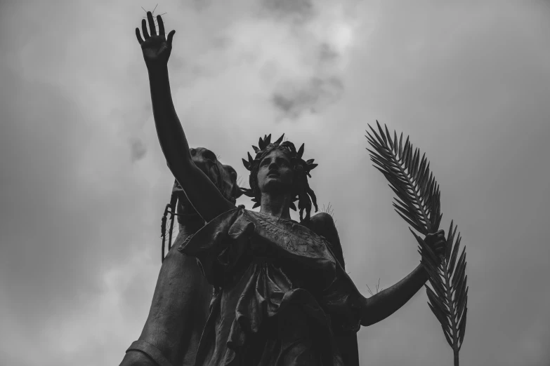 a statue in a city is holding up three palm trees