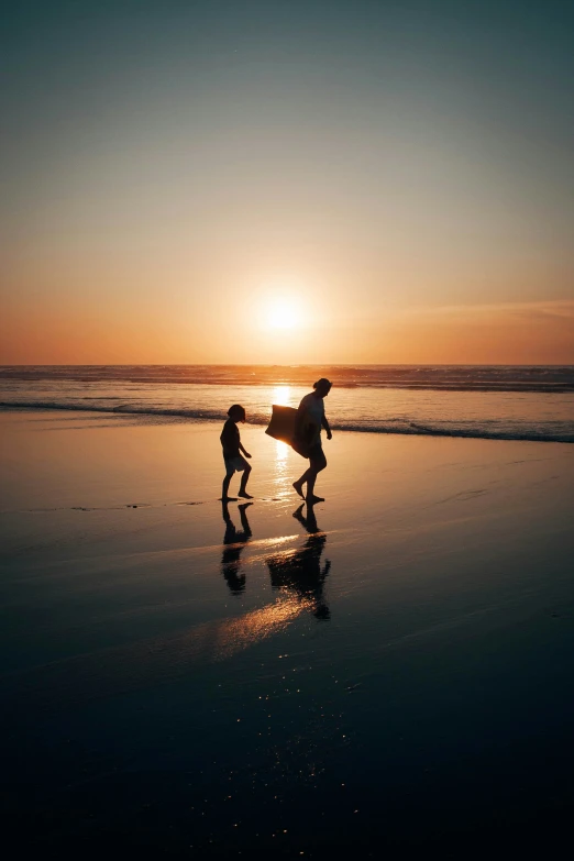 two people walk along the water while sunsets