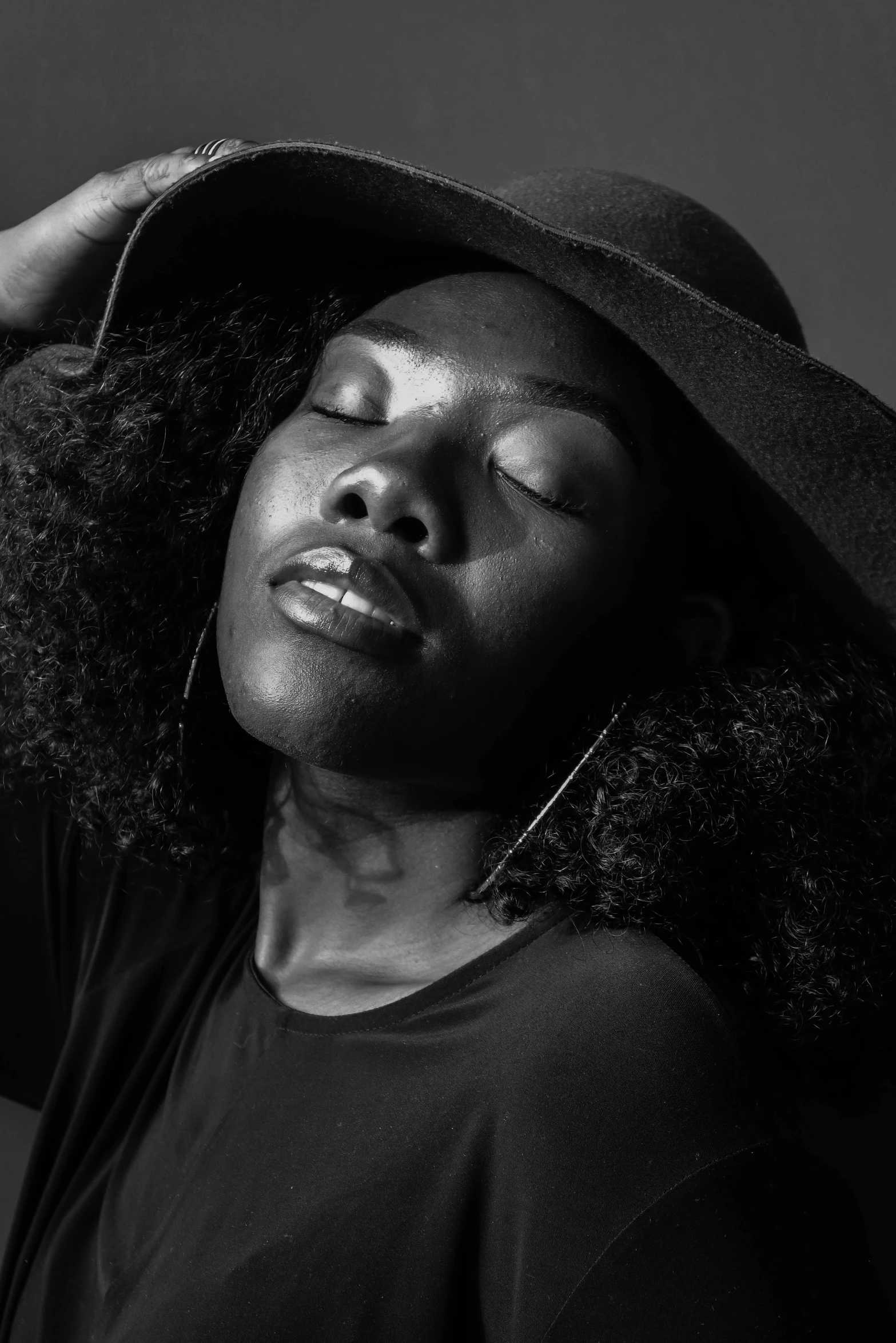 a black woman with her eyes closed wearing a black hat