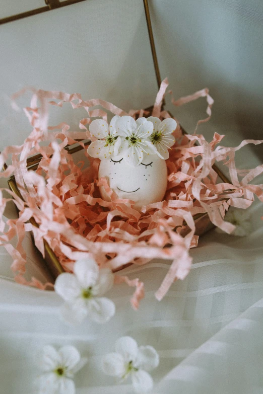 a tiny egg with flowers in it on top of pink tissue paper