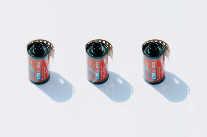 three orange cans sitting in the middle of white backdrop
