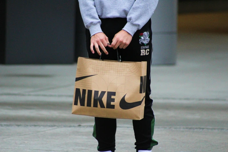 a woman holding a brown bag that reads nike