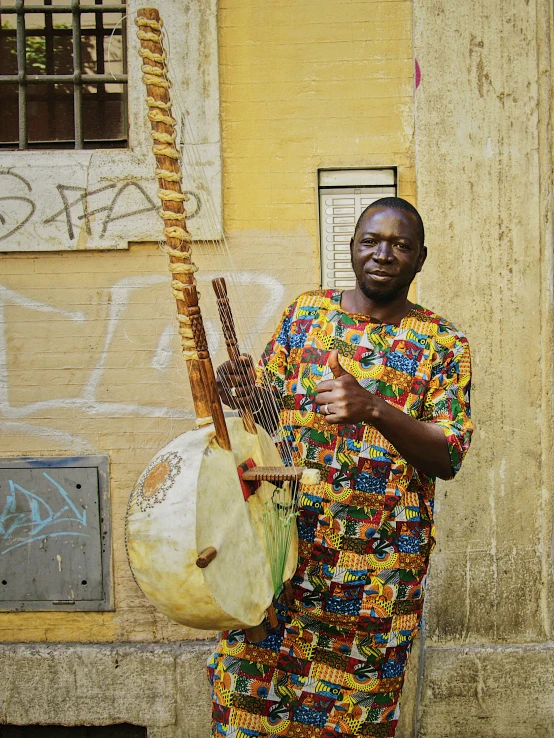 a black man in a brightly colored dress holding a instrument